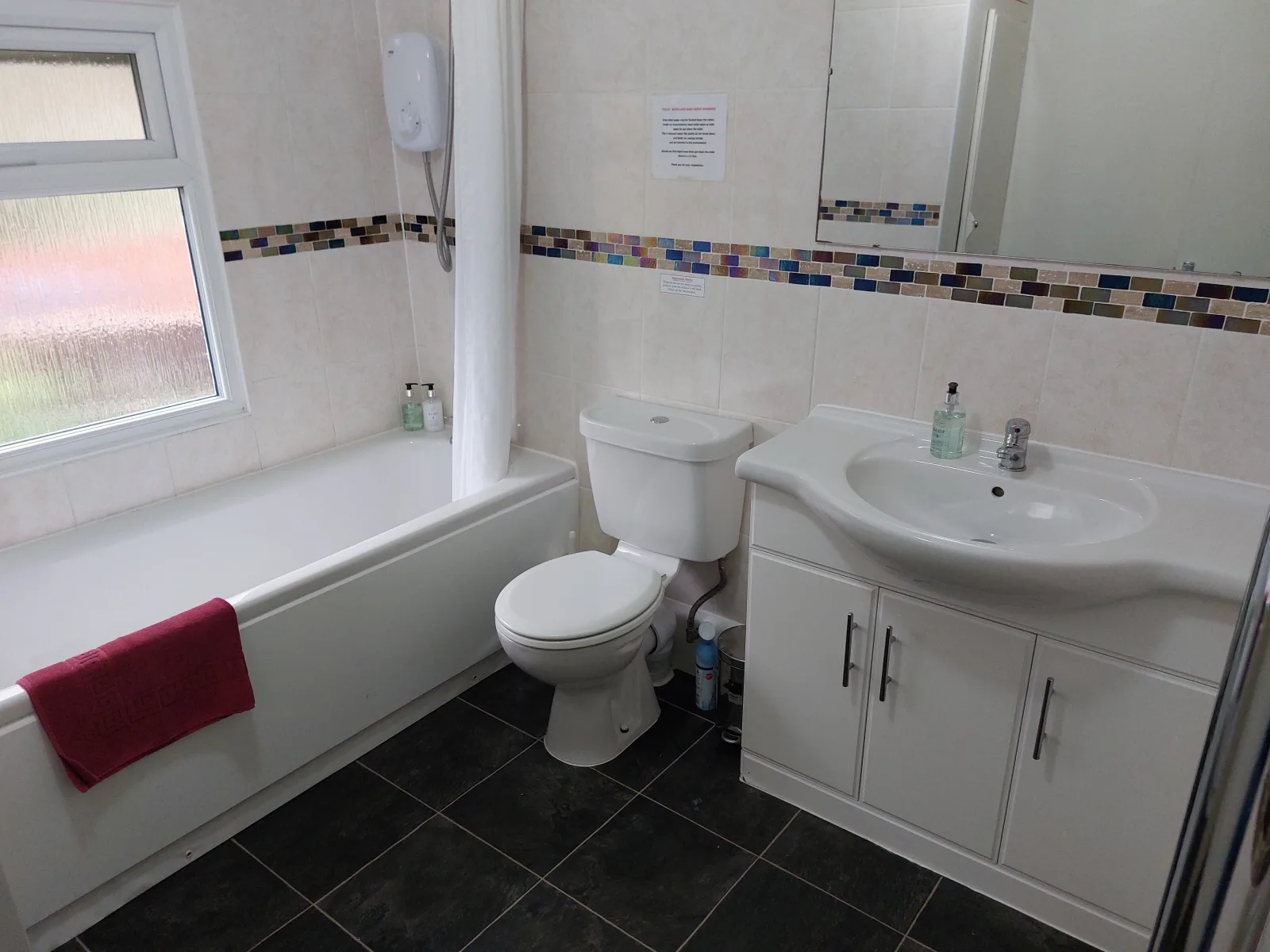Family bathroom at Waterside Cottage with a bath a WC and a basin and a slate tiled floor