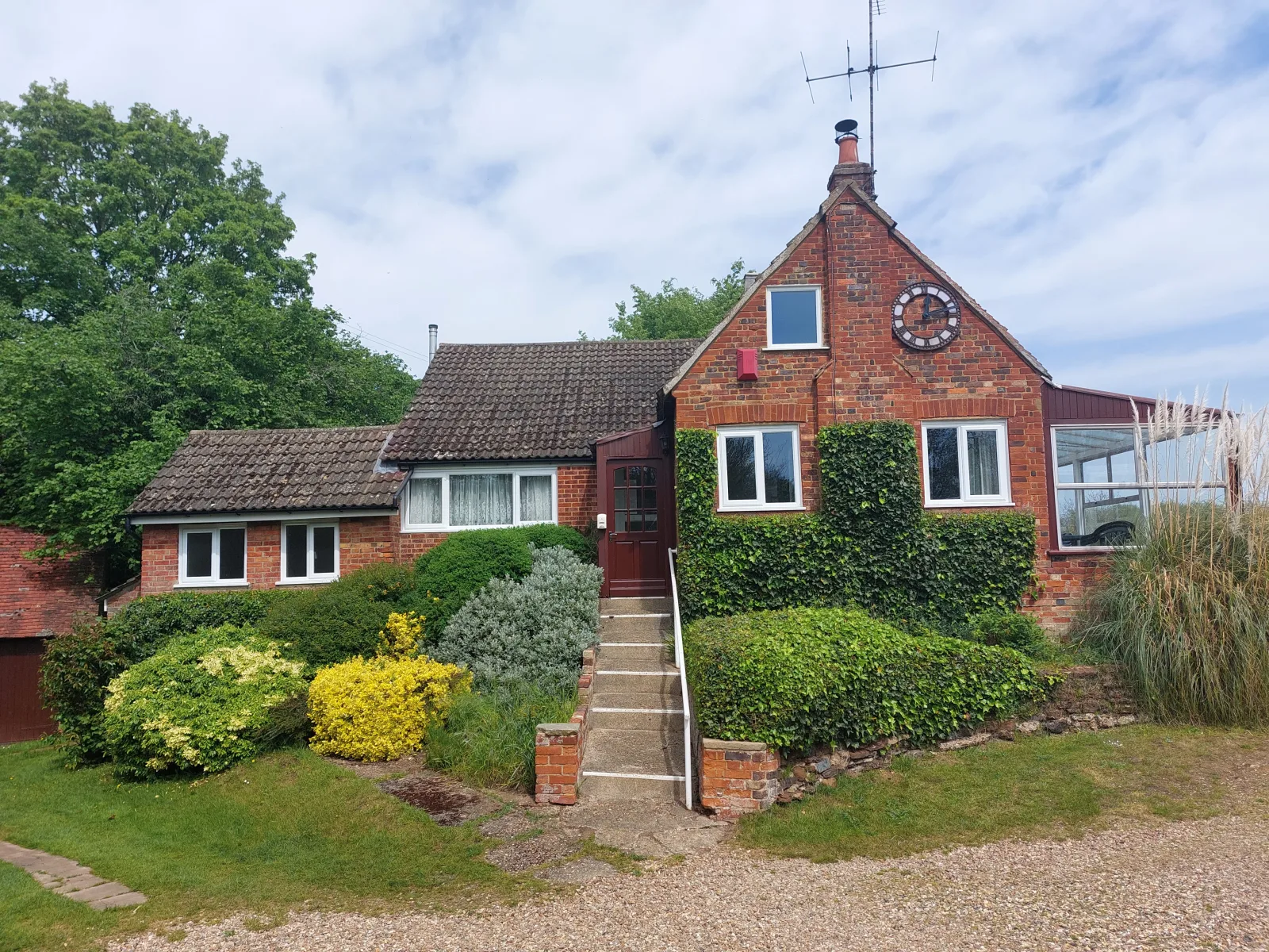 Brick-built Waterside Cottage seen from the driveway with steps up to the front door