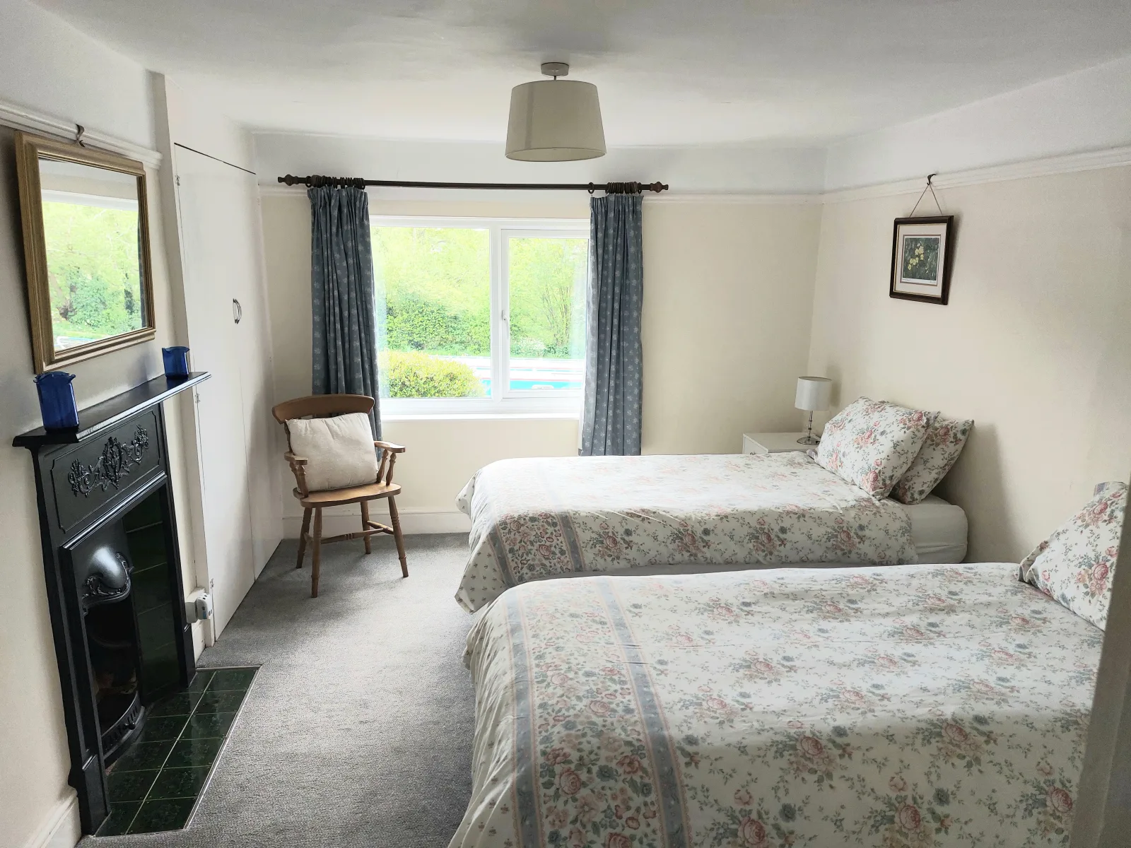 Twin bedroom at Waterside Cottage with a cast iron fireplace and a chair between the beds