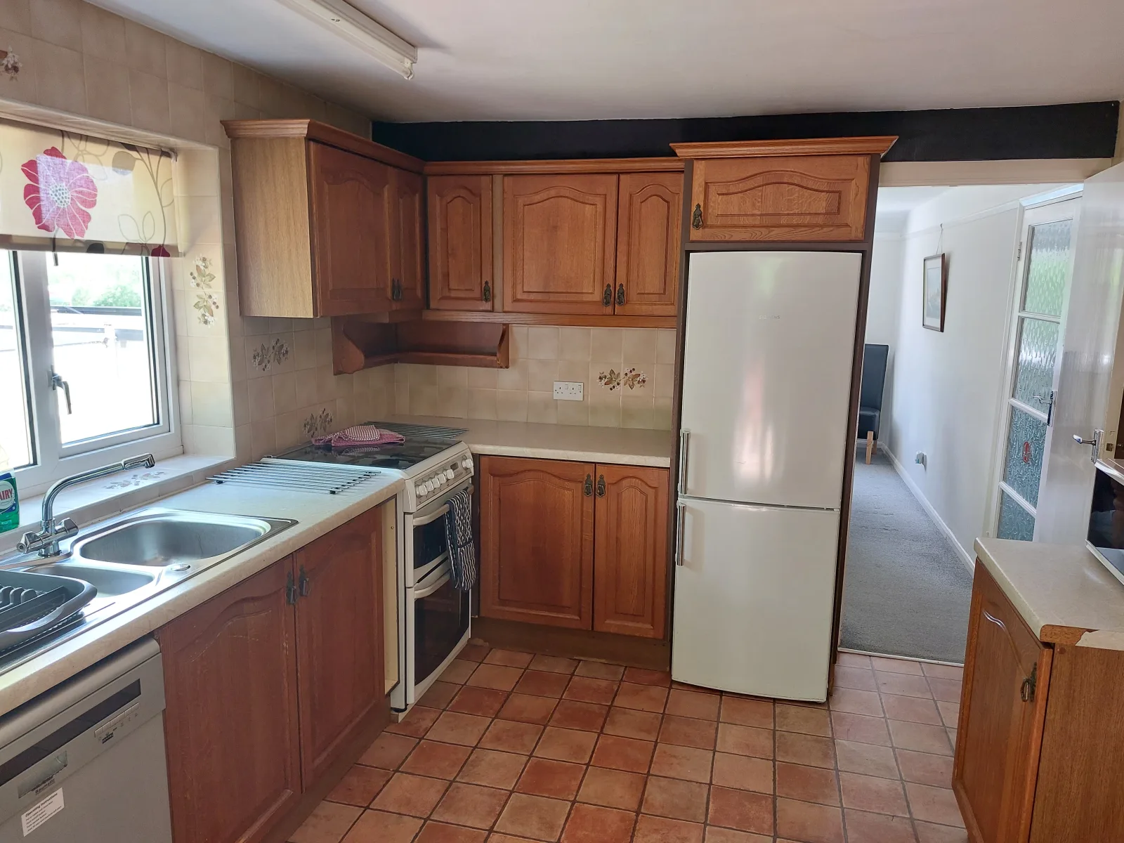 Kitchen at Waterside Cottage with wooden units a fridge freezer and a door through to the hall