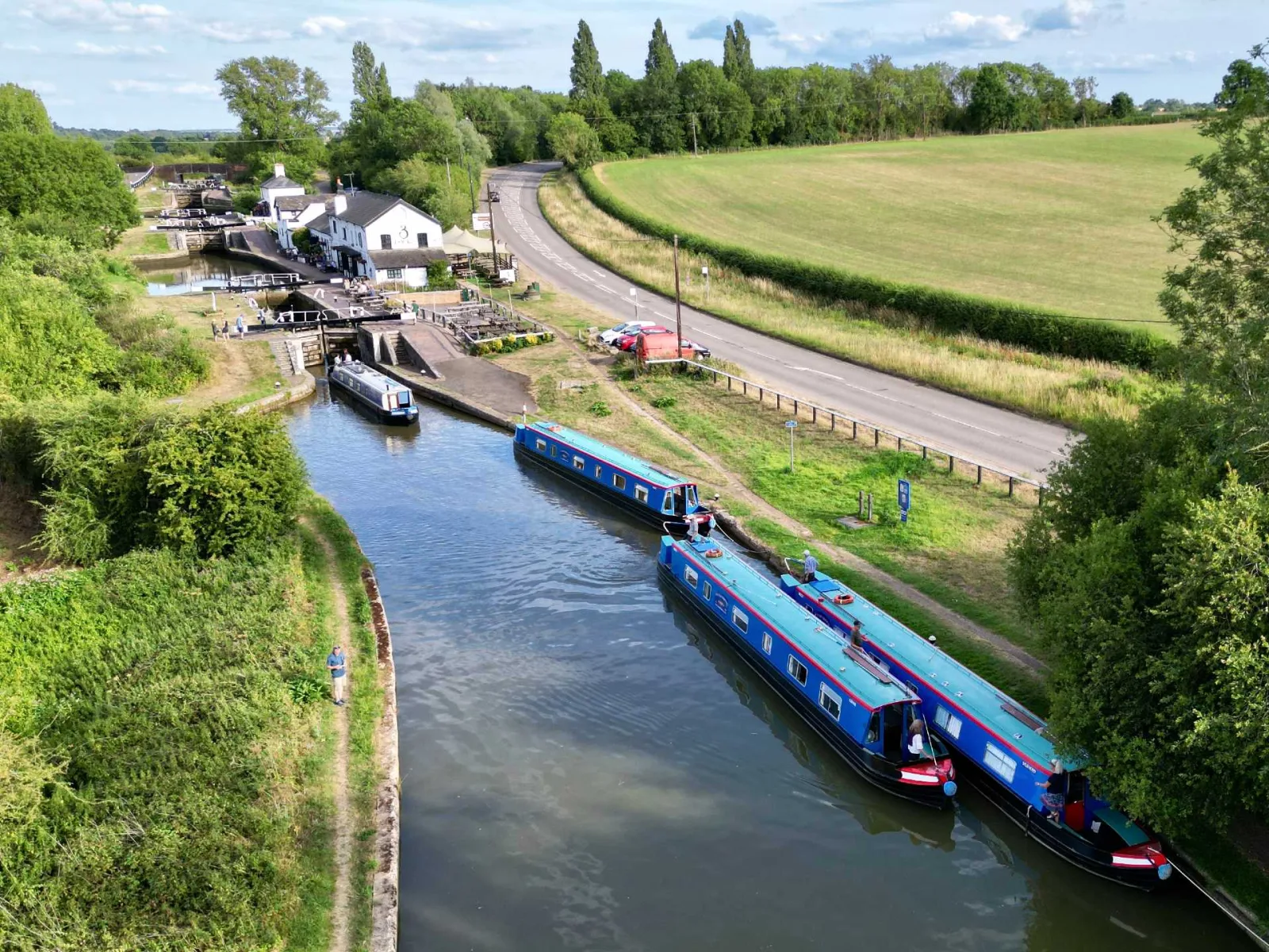 Aerial view of narrowboats moored at the Three Locks with the road and fields beyond