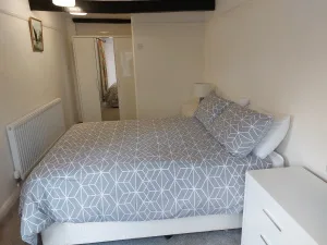 Double bedroom at Waterside Cottage with a patterned throw and a radiator under the window