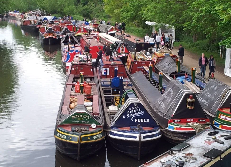 Dozens of traditional narrowboats moored two abreast at a canal gathering