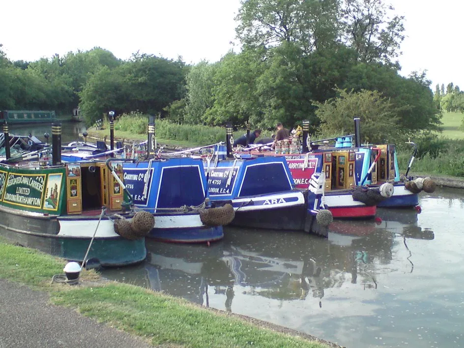 Row of brightly painted traditional narrowboats moored along the towpath