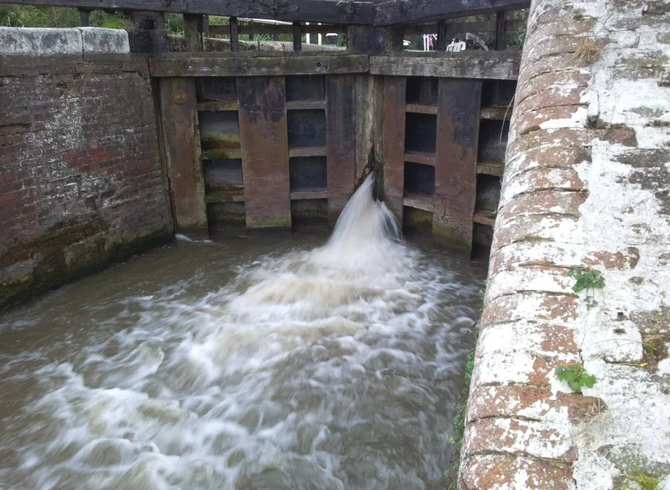 Water rushing through the paddles of a closed pair of lock gates