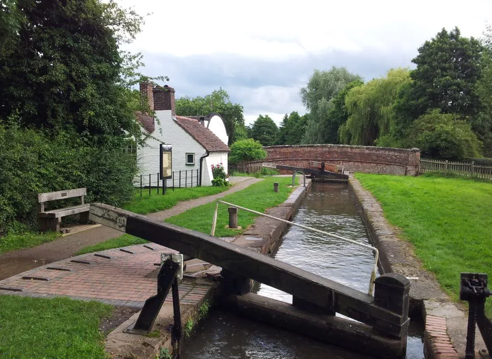 Empty narrow lock with the gates closed and a white lock cottage behind