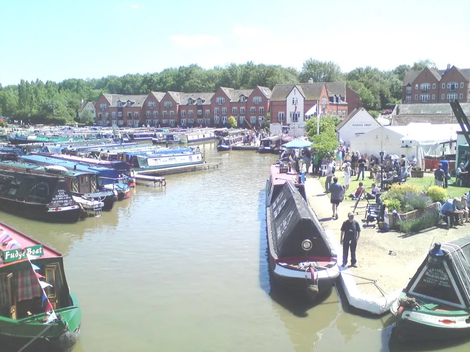 Busy canal basin lined with moored narrowboats and modern apartment buildings behind