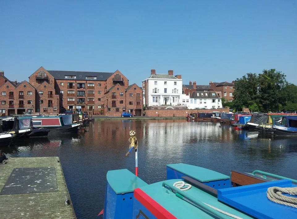 Narrowboats moored at a town canal basin with converted brick warehouses behind