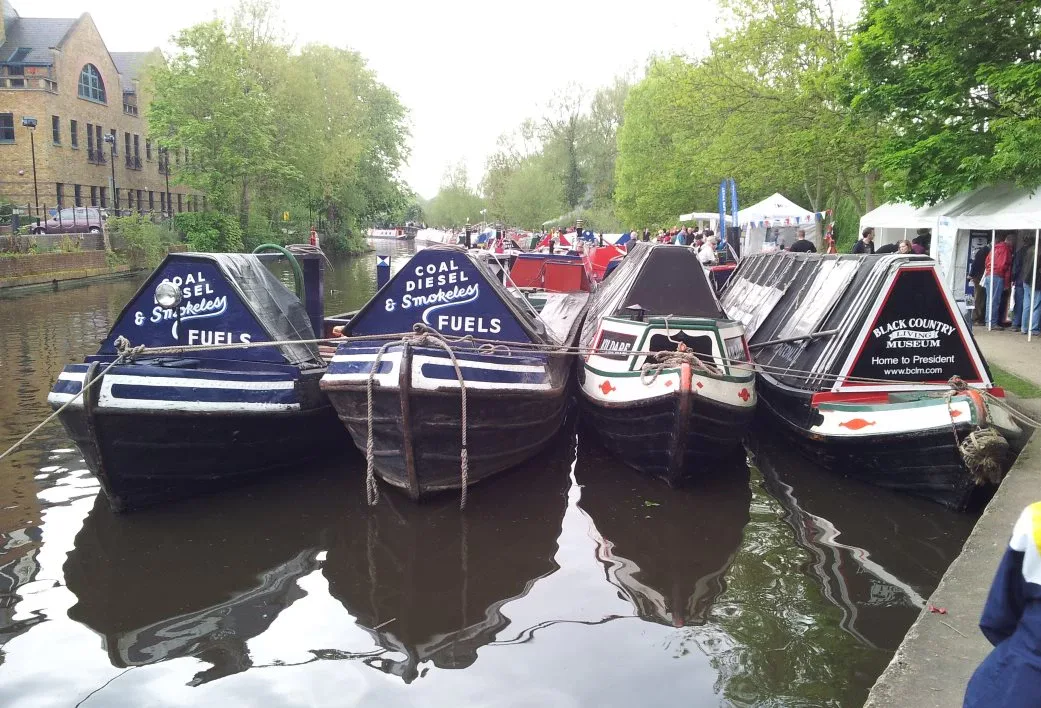 Row of traditional narrowboats moored side by side at a canal gathering
