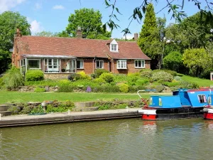 Waterside Cottage seen from across the canal with a narrowboat moored below the garden