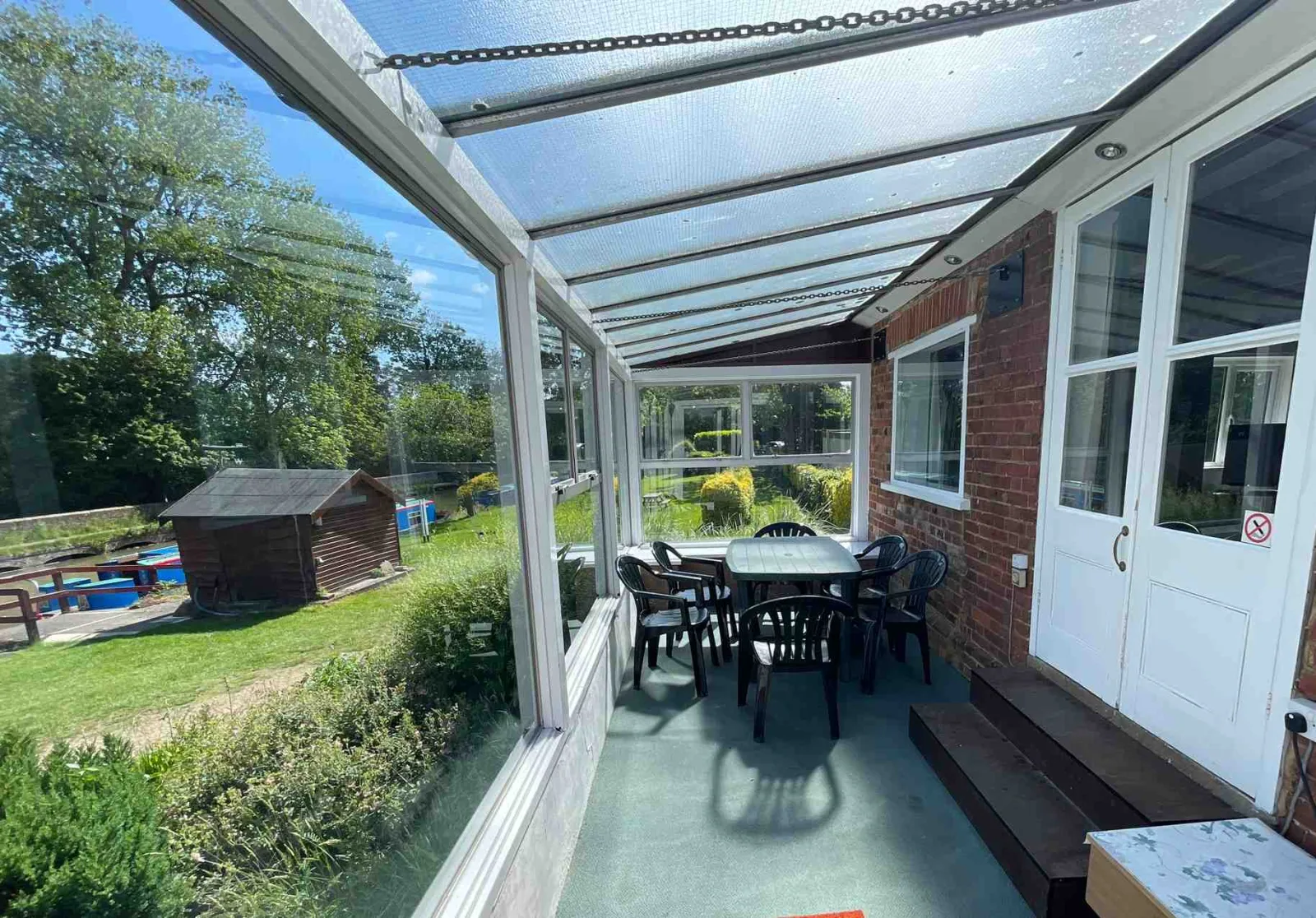 Inside the conservatory at Waterside Cottage with a dining table and doors to the terrace