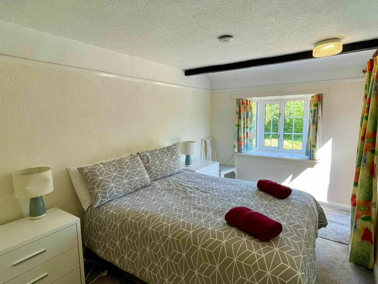 Double bedroom at Waterside Cottage with a beamed ceiling and a window over the garden