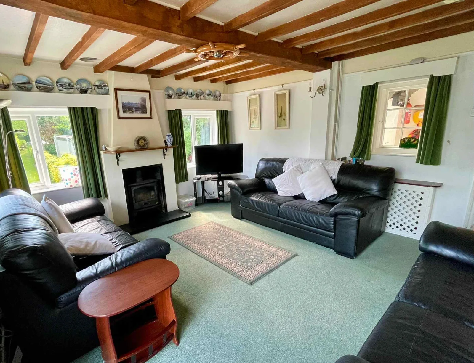 Living room at Waterside Cottage with leather sofas a television and doors to the garden