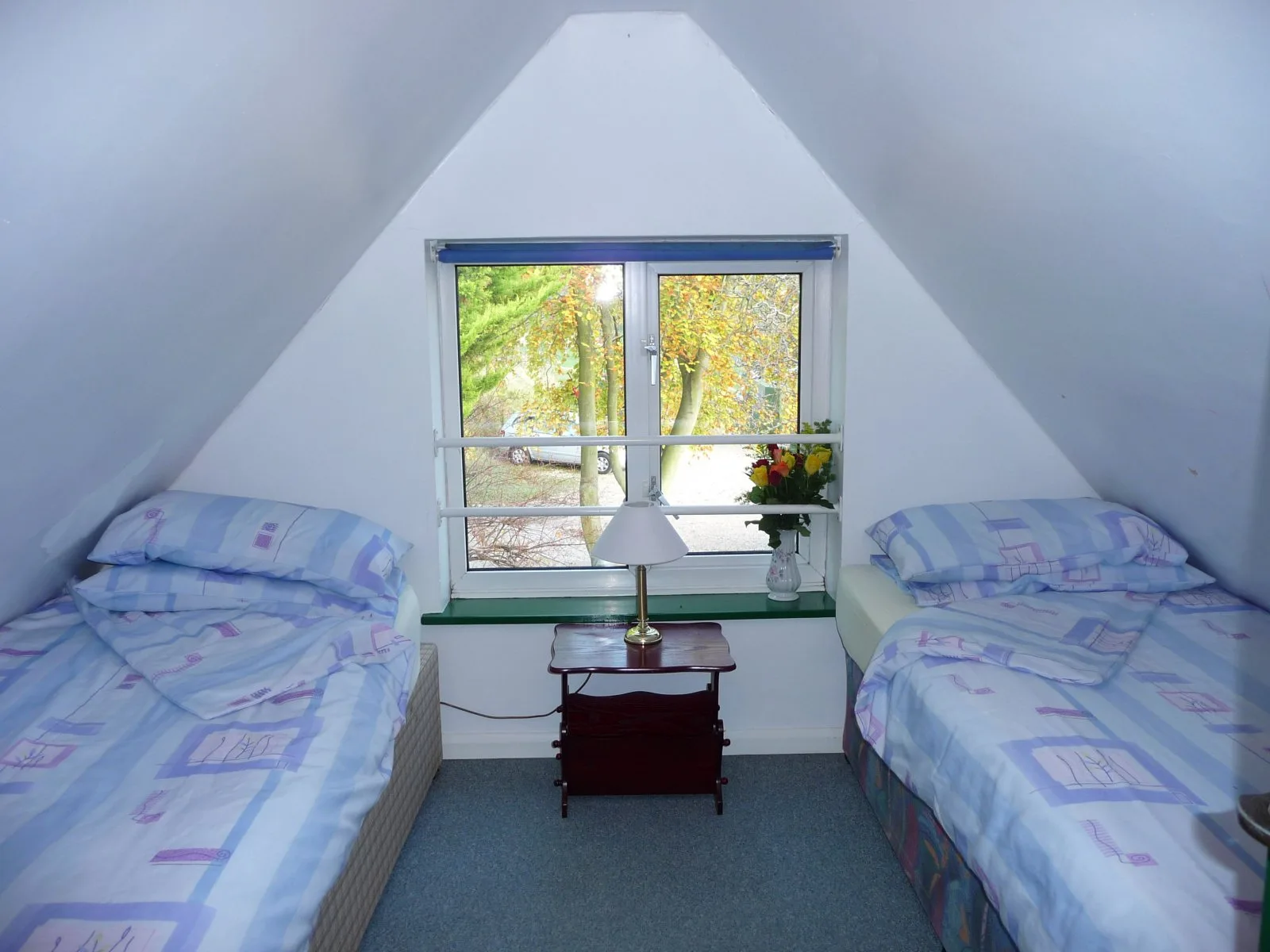 Twin loft bedroom at Waterside Cottage with sloping ceilings and a table between the beds